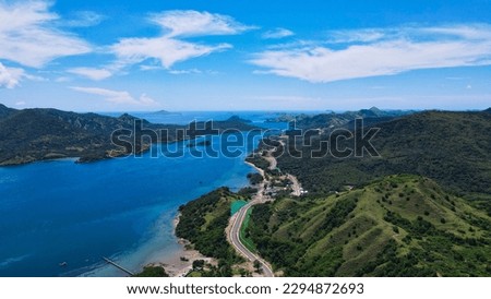Golo Mori – Labuan Bajo Super Premium Tourism Destination where Asean Summit will held. Aerial view of a road in green meadows and hills with beach and mountains. Road to Golo Mori Mice. Royalty-Free Stock Photo #2294872693