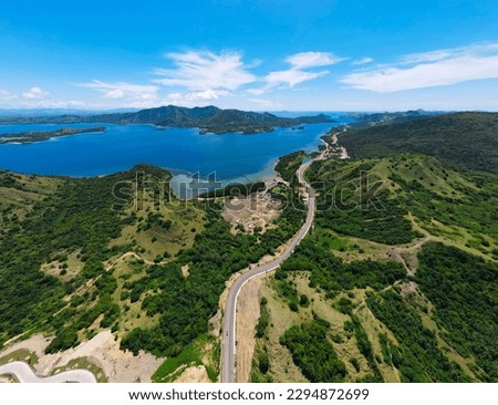 Golo Mori – Labuan Bajo Super Premium Tourism Destination where Asean Summit will held. Aerial view of a road in green meadows and hills with beach and mountains. Road to Golo Mori Mice. Royalty-Free Stock Photo #2294872699