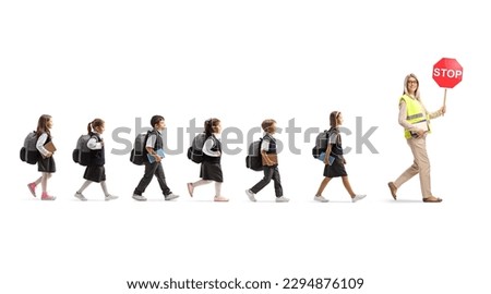 Full length profile shot of schoolchildren walking behind a teacher with stop traffic sign isolated on white background