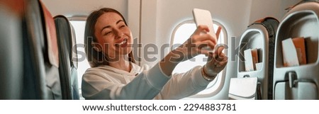 Cheerful young woman making selfie in airplane