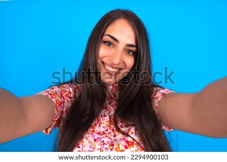 Photo of beautiful brunette woman wearing floral dress over blue background do selfie
