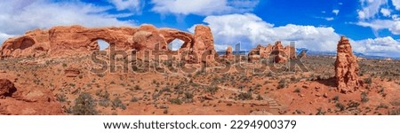 Panoramic view of North Window, South Window, and Turret Arch with beautiful clouds in the sky, small figures of people in the frame emphasize the scale and beauty of this majestic creation, Moab, USA Royalty-Free Stock Photo #2294900379