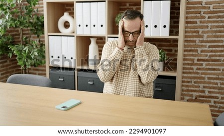 Middle age man business worker stressed sitting on table at office