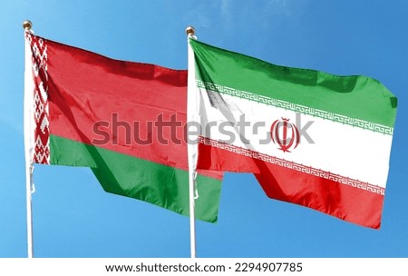 Iran flag and Belarus flag on cloudy sky. waving in the sky Royalty-Free Stock Photo #2294907785