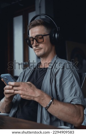 Young man using smartphone in hand, cafe, office,listening music on headphones, music streaming on smartphone, happy face, mp3, love sound, high fi less, dreams moods, concept, AirPods max, love,
