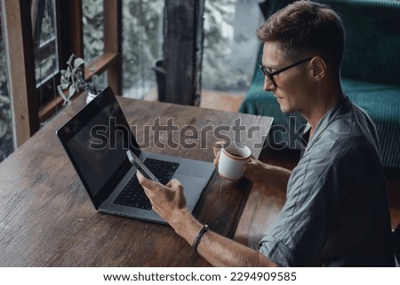 Young man using smartphone in hand, cafe, office,outdoor portrait business man, hipster style, internet, smartphone, office, Bali Indonesia, holding, mac OS, manager, freelancer, concept, laptop