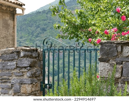 Green gate opening onto lovely green hillside with pink flowers around. High quality photo