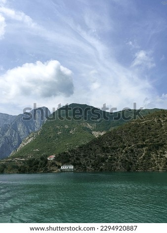 View of little white house on the edge of tranquil Lake Koman with cloudscape and copy space, Albania, Balkans. High quality photo