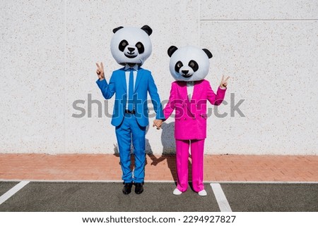 Storytelling image of a couple wearing giant panda head and colored suits. Man and woman making party in a parking lot. Royalty-Free Stock Photo #2294927827