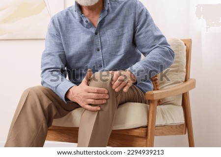 Senior man suffering from pain in his knee at home, closeup. Arthritis symptoms Royalty-Free Stock Photo #2294939213