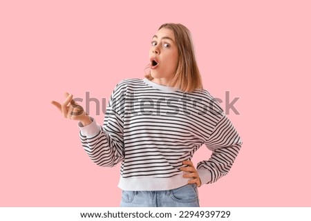 Young woman in striped sweatshirt snapping fingers on pink background