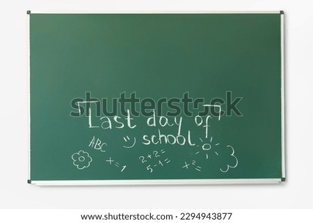 Blackboard with text LAST DAY OF SCHOOL and drawings on white wall Royalty-Free Stock Photo #2294943877
