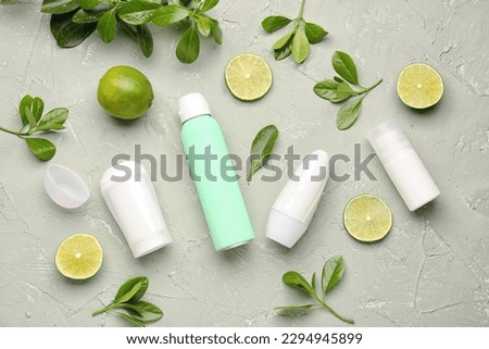 Different deodorants, leaves and lime on grunge background Royalty-Free Stock Photo #2294945899