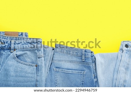 Stylish jeans on yellow background