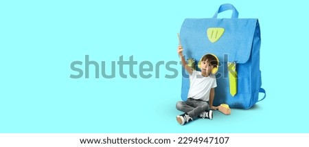 Little boy and big schoolbag on light blue background with space for text