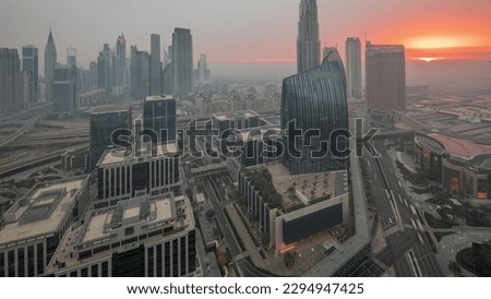 Futuristic Dubai Downtown and finansial district skyline aerial night to day transition . Many illuminated towers and skyscrapers with morning fog before sunrise