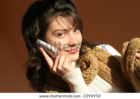 Woman with cell mobile phone on a suit and against a brown background.