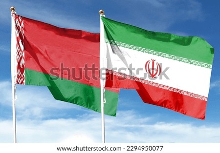Iran flag and Belarus flag on cloudy sky. waving in the sky Royalty-Free Stock Photo #2294950077