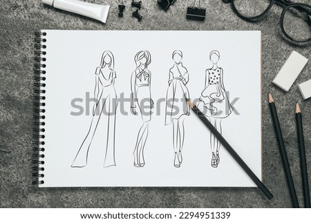 Sketches of different clothes in pad on grey textured table. Fashion designer's desk with stationery, flat lay Royalty-Free Stock Photo #2294951339