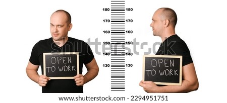 Young man in search of work holds a sign with the inscription "open to work" against background of prison height meter. Creative photo of the concept of unemployment. Comic representation of criminals Royalty-Free Stock Photo #2294951751
