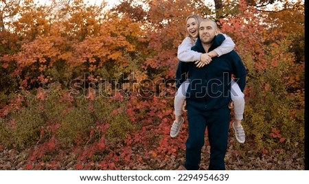 Happy couple in love newlyweds in sports clothes walk in the autumn forest. Young smiling family enjoying fall in the park. Copy space