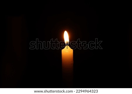 One burning wax candle on black background