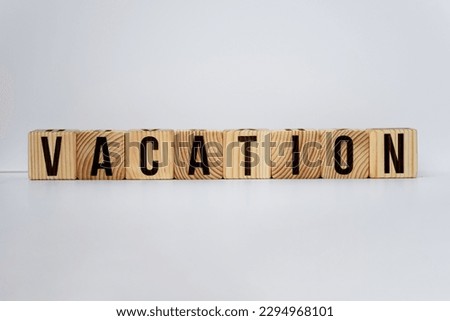 word vacation written in small wooden alphabet cubes on isolated white background, travel concept