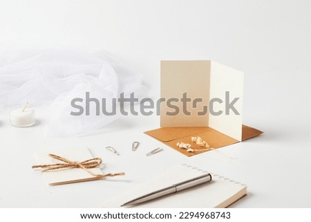 Mock up of a blank white greeting card in a solid white background with aesthetic object surrounding it. Royalty-Free Stock Photo #2294968743