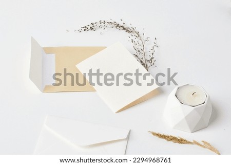 Mock up of a blank white greeting card in a solid white background with aesthetic object surrounding it.