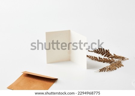 Mock up of a blank white greeting card in a solid white background with aesthetic object surrounding it.