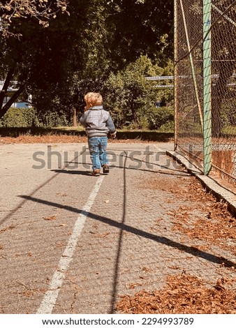 boy 2 years old walking near the basketball court
