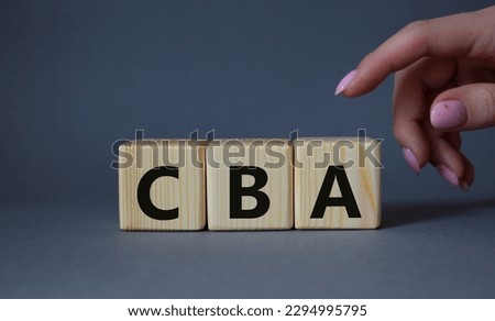 CBA - Cost Benefit Analysis symbol. Wooden cubes with word CBA. Beautiful grey background. Businessman hand. Business and Cost Benefit Analysis concept. Copy space.