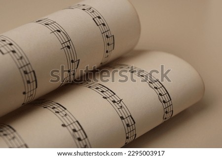 Rolled sheets with music notes on light background, closeup