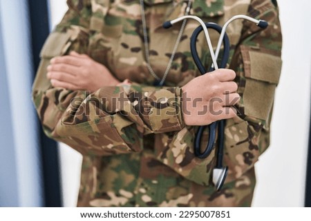 Young hispanic woman army doctor holding stethoscope at home