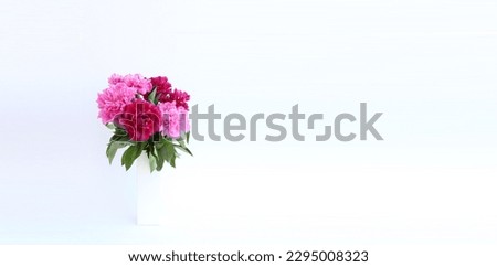 This stunning bouquet features lush and beautiful peonies in various shades of pink, elegantly arranged in a white vase on a pristine white background. Perfect for adding a touch of romance and sophis