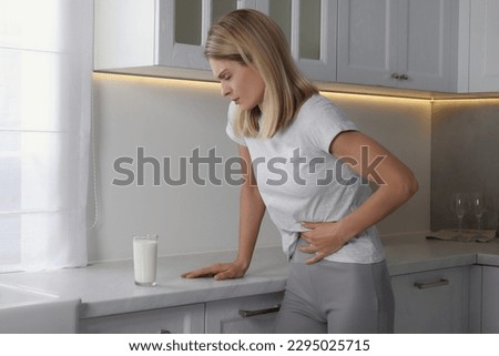Woman suffering from lactose intolerance in kitchen Royalty-Free Stock Photo #2295025715