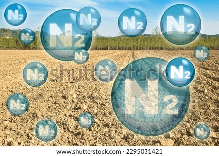 N2 nitrogen gas is the main constituent of the earth's atmosphere - concept with nitrogen molecules against a plowed field Royalty-Free Stock Photo #2295031421