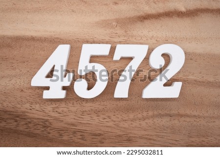 White number 4572 on a brown and light brown wooden background.