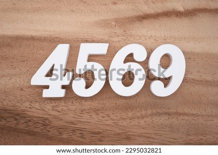 White number 4569 on a brown and light brown wooden background.