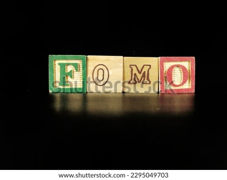 "FOMO" spelled out on a wooden cube. "FOMO" means fear of missing out.