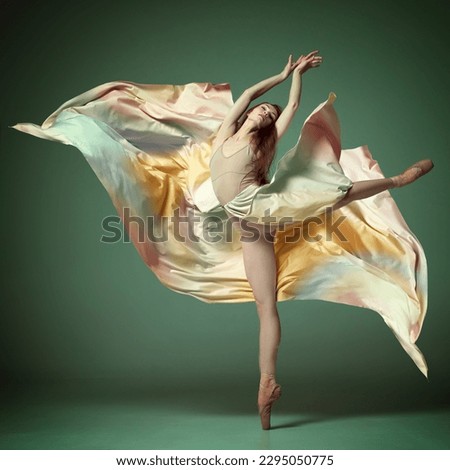 Graceful jump. Portrait of beautiful ballerina, dancer wearing colorful dress over dark green background. Contemporary dance. Concept of classic ballet, inspiration, beauty, dance, creativity