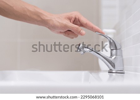 Save water. Volunteer keeps turning off the running water in the bathroom to protect environment. Greening planet, reduce global warming, Save world, life, future, risk energy, crisis , water day. Royalty-Free Stock Photo #2295068101