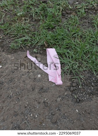 pink ribbon wasted on a grass field after being played by children in bogor Royalty-Free Stock Photo #2295069037