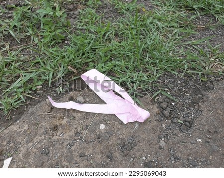 pink ribbon wasted on a grass field after being played by children in bogor Royalty-Free Stock Photo #2295069043