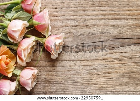 Pastel pink roses on wooden background. Copy space