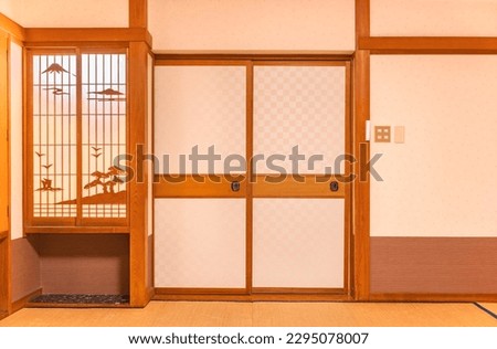 Wall of a typical traditional Japanese room featuring tatami mats covering the floor, fusuma doors and shoji window made of rice paper with wooden decorations evocating a landscape of the mount Fuji. Royalty-Free Stock Photo #2295078007