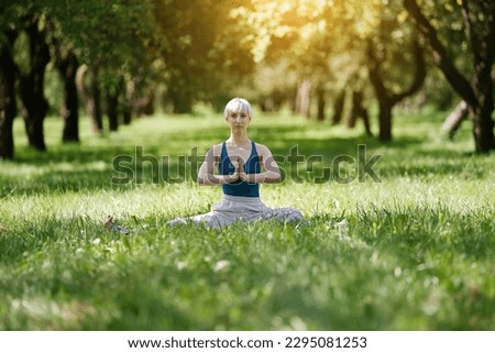 Young woman doing yoga exercise outdoor in the park, sport yoga concept                               