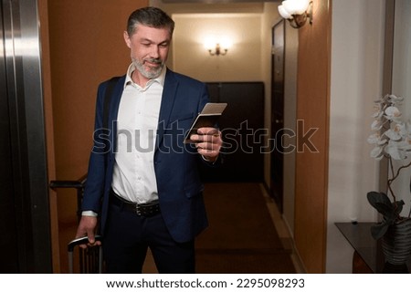 Adult man standing in the hotel corridor Royalty-Free Stock Photo #2295098293