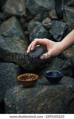 Tea ceremony in mountains, Oolong tea in a beautiful landscape, Girl hand holding blue cup with tea. A tea ceremony at rocks. The way of spending time with friends in nature.