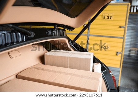 Cardboard boxes lying in the automobile trunk in the warehouse
